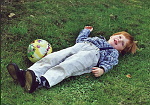 Dreng med bold i græsset.